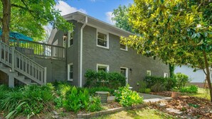 A two-story house with a covered porch and a small garden area. - White Oak 4BR @ Patterson Place (Durham)