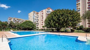 Une piscine entourée de verdure et de grands immeubles d’habitation.