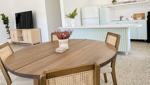 Une cuisine moderne dotée d’un îlot central, de meubles blancs et d’un coin repas avec une table et des chaises en bois.