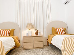 Ein Doppelzimmer mit zwei Betten, einem Nachttisch mit Lampe und einer kleinen Holzkabine.