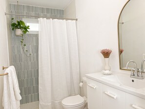 Ein Badezimmer mit Toilette, Waschbecken mit Spiegel und Duschvorhang.