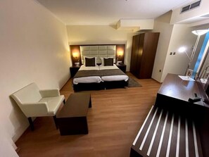 A modern hotel room with a large bed, a desk, a chair, and a wardrobe. - Europa Hotel (Kastoria)