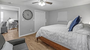 A bedroom with a bed, a ceiling fan, a desk with a chair, and a wall decoration. - Clean, comfortable home. (Marion)
