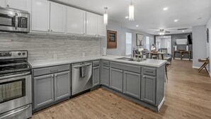 A modern kitchen with grey cabinets, stainless steel appliances, and a wooden floor. - Clean, comfortable home. (Marion)