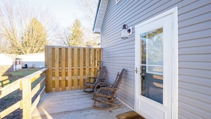 A wooden deck with rocking chairs and a wooden fence. - Clean, comfortable home. (Marion)