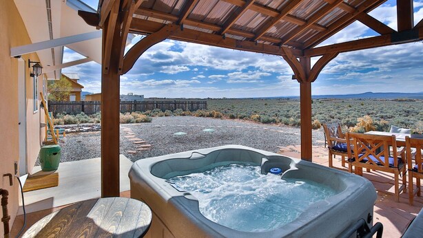Un bain à remous sous une pergola en bois, avec vue sur un paysage désertique.