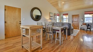 Un vaste salon doté d’un plafond en bois, un coin repas avec une table et des chaises en bois, et un grand miroir accroché au mur.