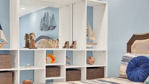 Une chambre à coucher comprenant un lit, un grand miroir et des étagères ornées de divers objets décoratifs.