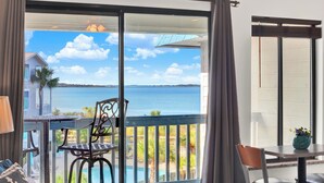 Un balcon avec vue sur la mer, une piscine et un coin repas avec une table et des chaises.