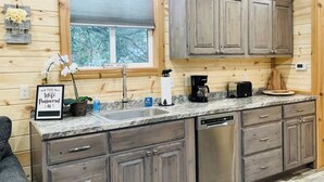A wooden cabin interior with a kitchen area, including cabinets, a sink, and a coffee maker.