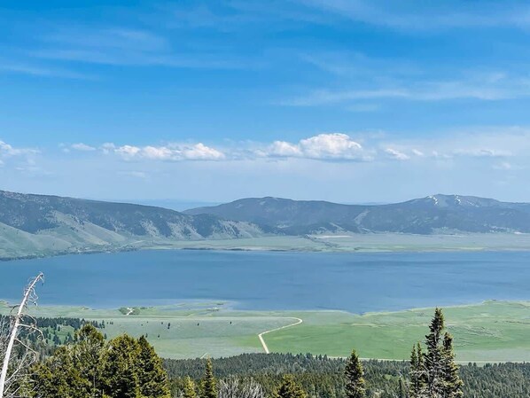 A panoramic view of a lake surrounded by hills and forested areas.