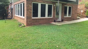 A two-story house with a brick facade, large windows, and a wooden deck. - ADA King near Crabtree, PNC Arena, State Fairgrounds, NCMA (Raleigh)