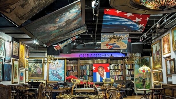 Una habitación con una biblioteca, un retrato y una araña.