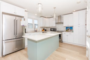 Una cocina moderna con electrodomésticos de acero inoxidable, una isla grande y armarios blancos.