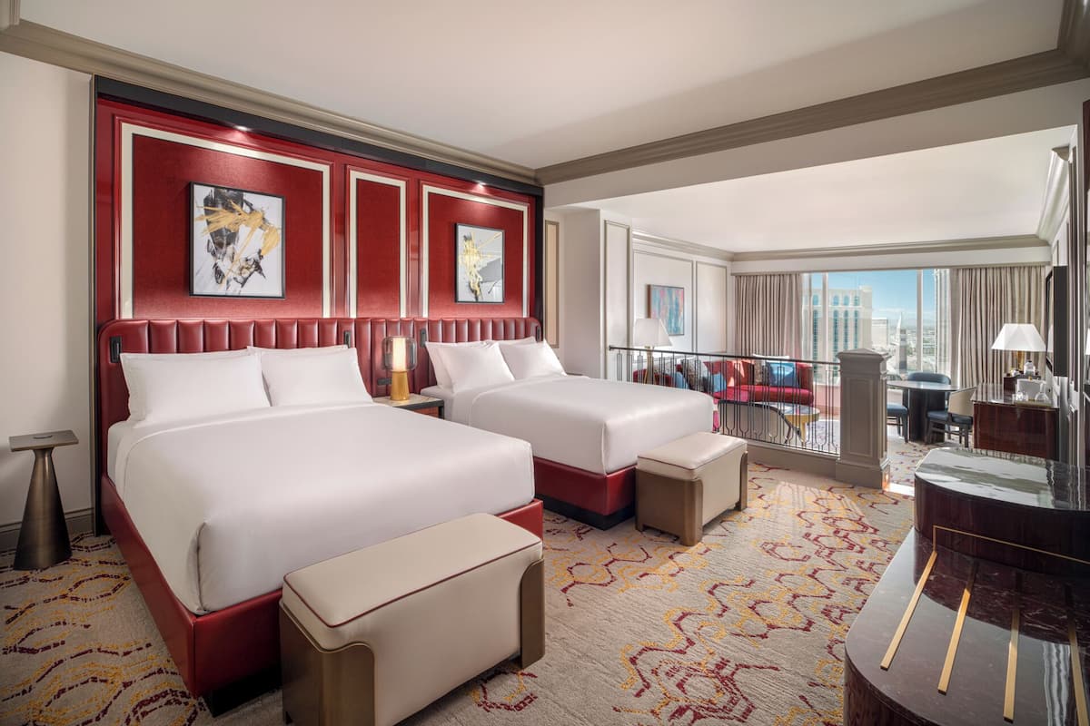 Une chambre d’hôtel avec deux lits, un balcon donnant sur la ville et un coin repas.