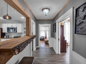 A modern kitchen with white cabinets, a stainless steel microwave, and a wooden countertop.