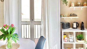 Un coin repas comprenant une table, des chaises, un vase de fleurs et une étagère avec des ustensiles de cuisine.