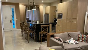 Ein modernes Wohnzimmer mit einer Sofagarnitur, einem Essbereich mit Stühlen und einer Küche mit Holzausstattung.