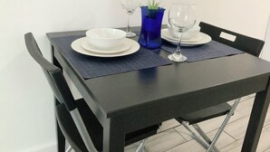 A dining table set with white plates, blue glassware, and a small plant.