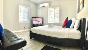 A bedroom with a bed, a television, and a window with blinds.