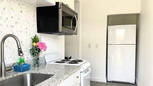 A kitchen with a stainless steel sink, a gas stove, a microwave, and a white refrigerator.