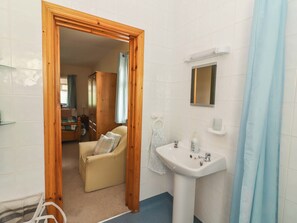 A bathroom with a wooden door, a sink, a mirror, and a shower curtain. - Moybella Lodge (Lisselton)