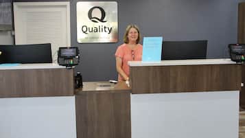 Un comptoir d’accueil d’hôtel avec une enseigne indiquant « Qualité garantie par Choice Hotels » et un écran Samsung.