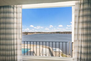 A view from a balcony with a pool, a bridge in the distance, and a clear sky.