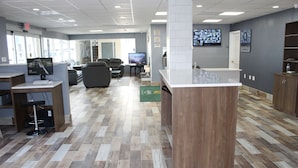 A modern reception area with a wooden reception desk, a television, comfortable seating, and a large window providing natural light. - Quality Inn - On The Lake Clarksville-Boydton  (Clarksville)