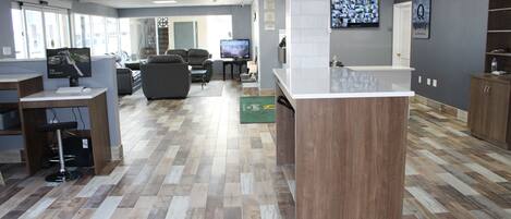 A modern reception area with a wooden reception desk, a television, comfortable seating, and a large window providing natural light.