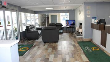 A hotel reception area with leather sofas, a television, and a reception desk.