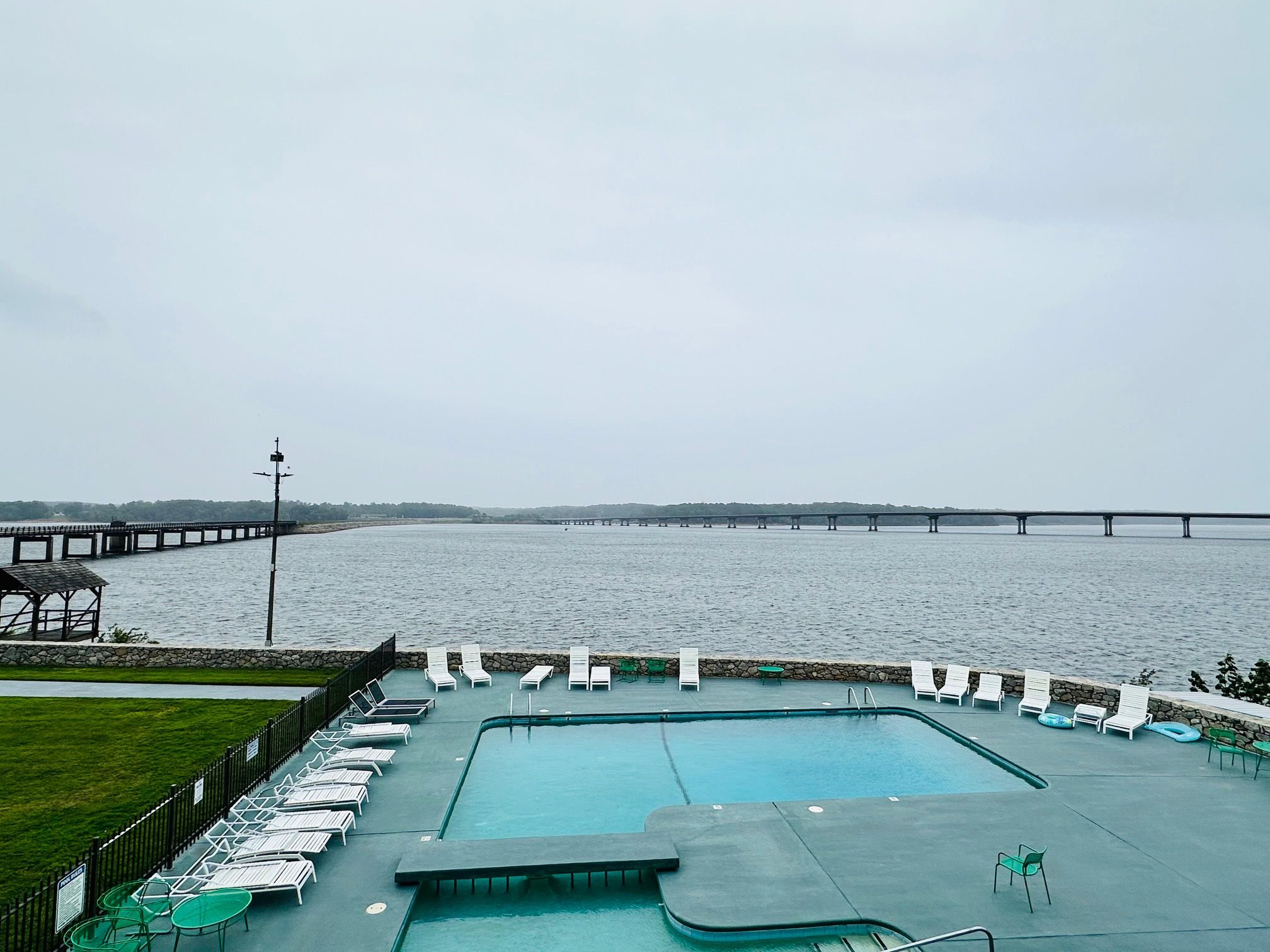 A swimming pool with lounge chairs and a view of a bridge over water.