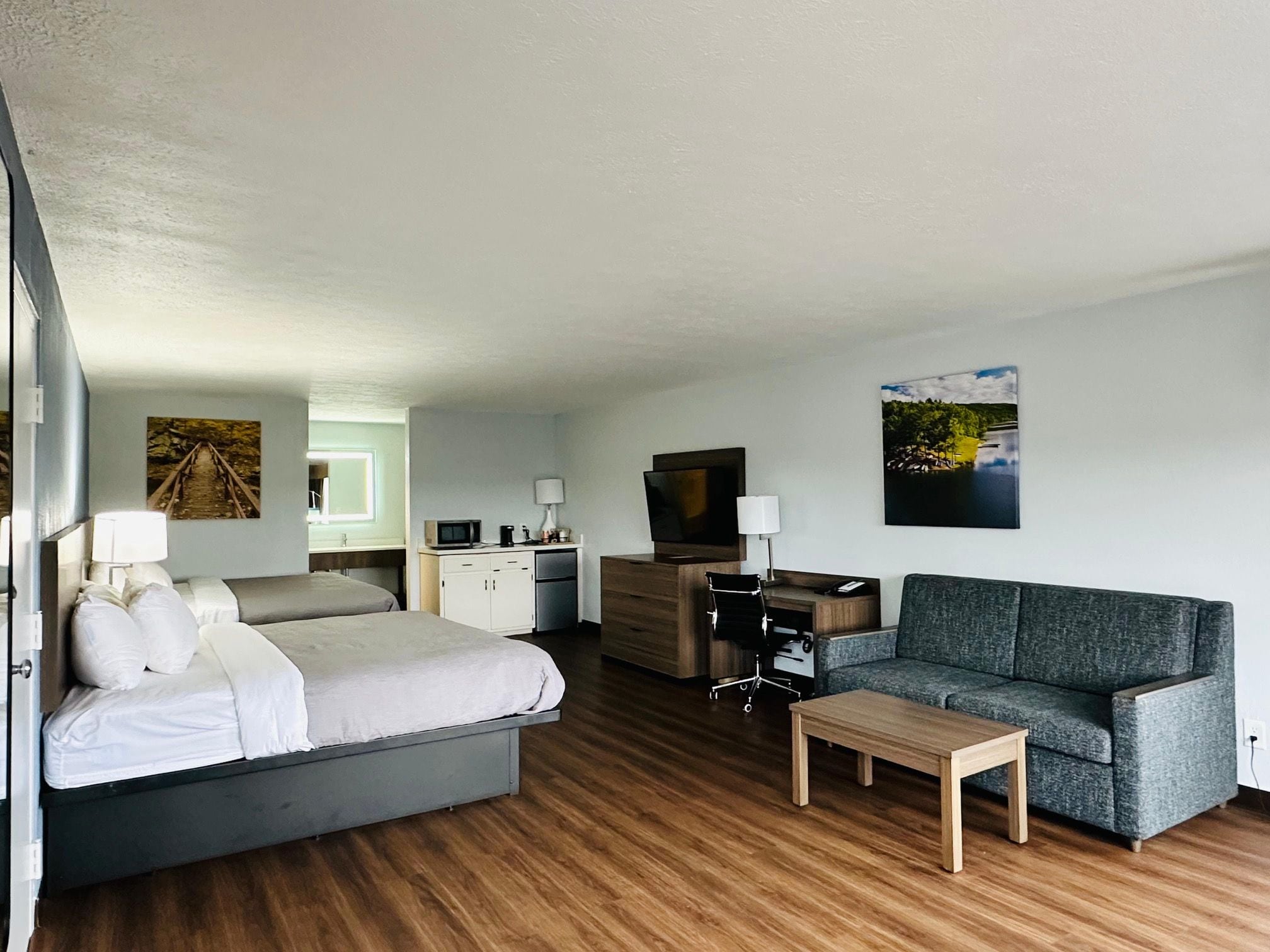 A hotel room with a bed, a sofa, a TV, a desk, and a small table.