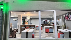 A modern interior with a brick wall, a green-lit ceiling, and a seating area with tables and chairs. - Quality Inn - On The Lake Clarksville-Boydton  (Clarksville)