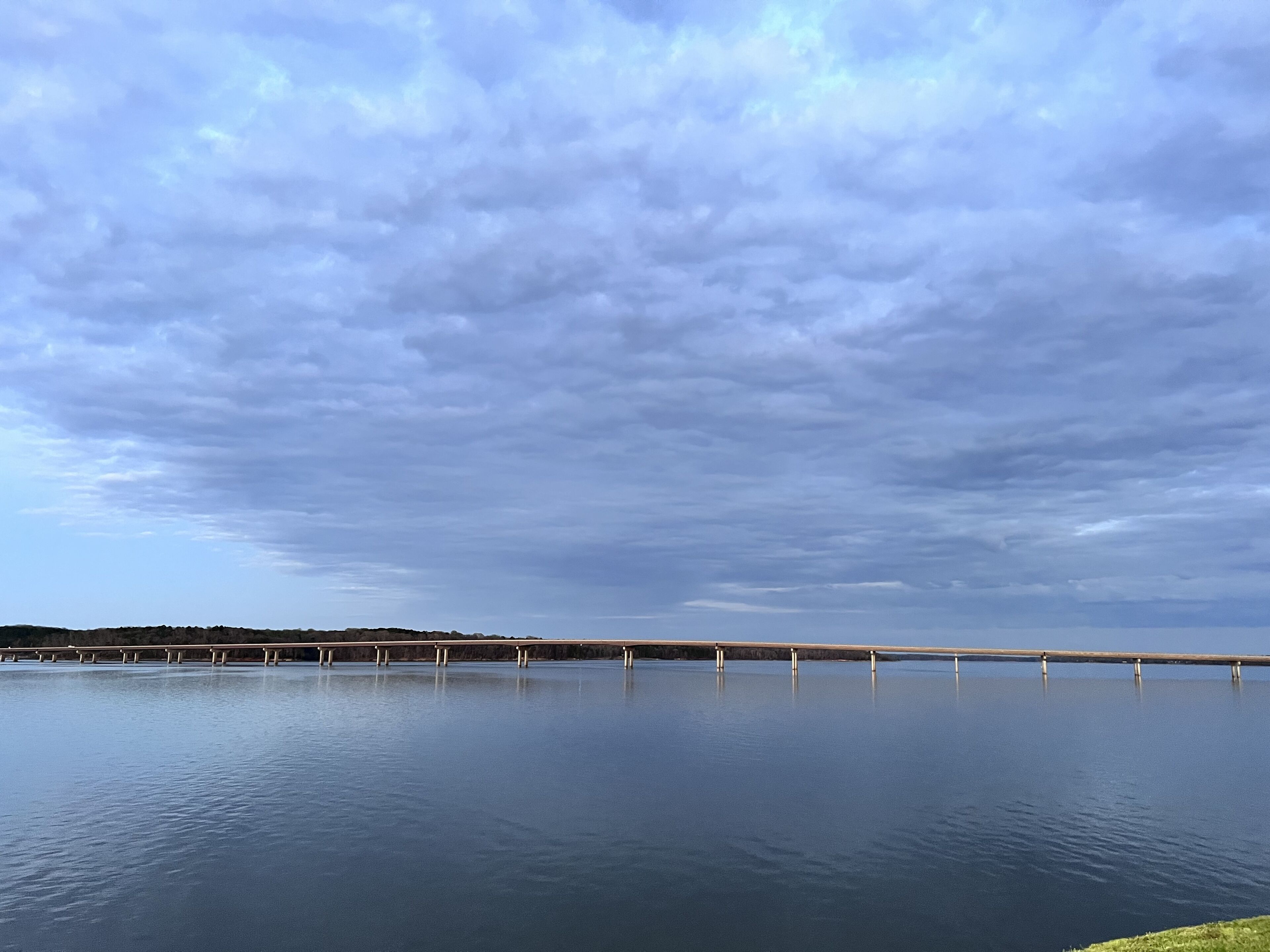 Una masa de agua tranquila con un puente que la cruza.