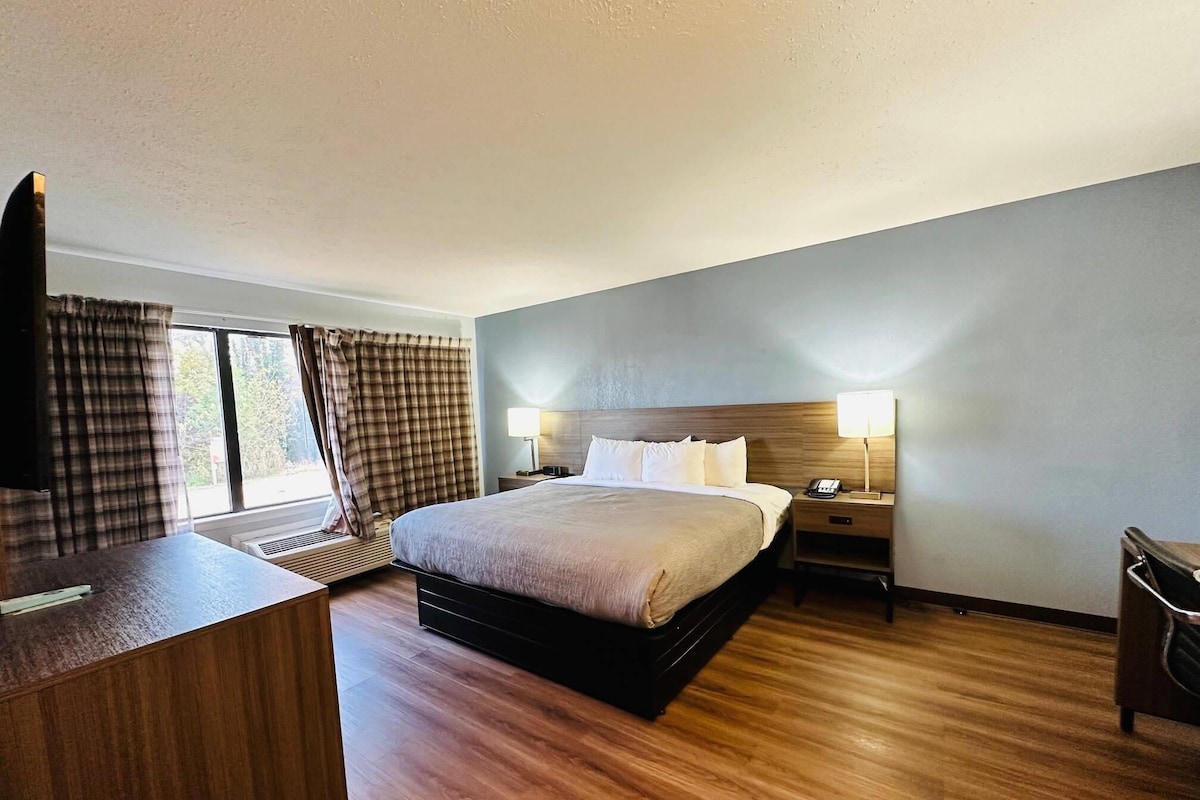 A hotel room with a large bed, two bedside tables with lamps, a desk, and a TV.