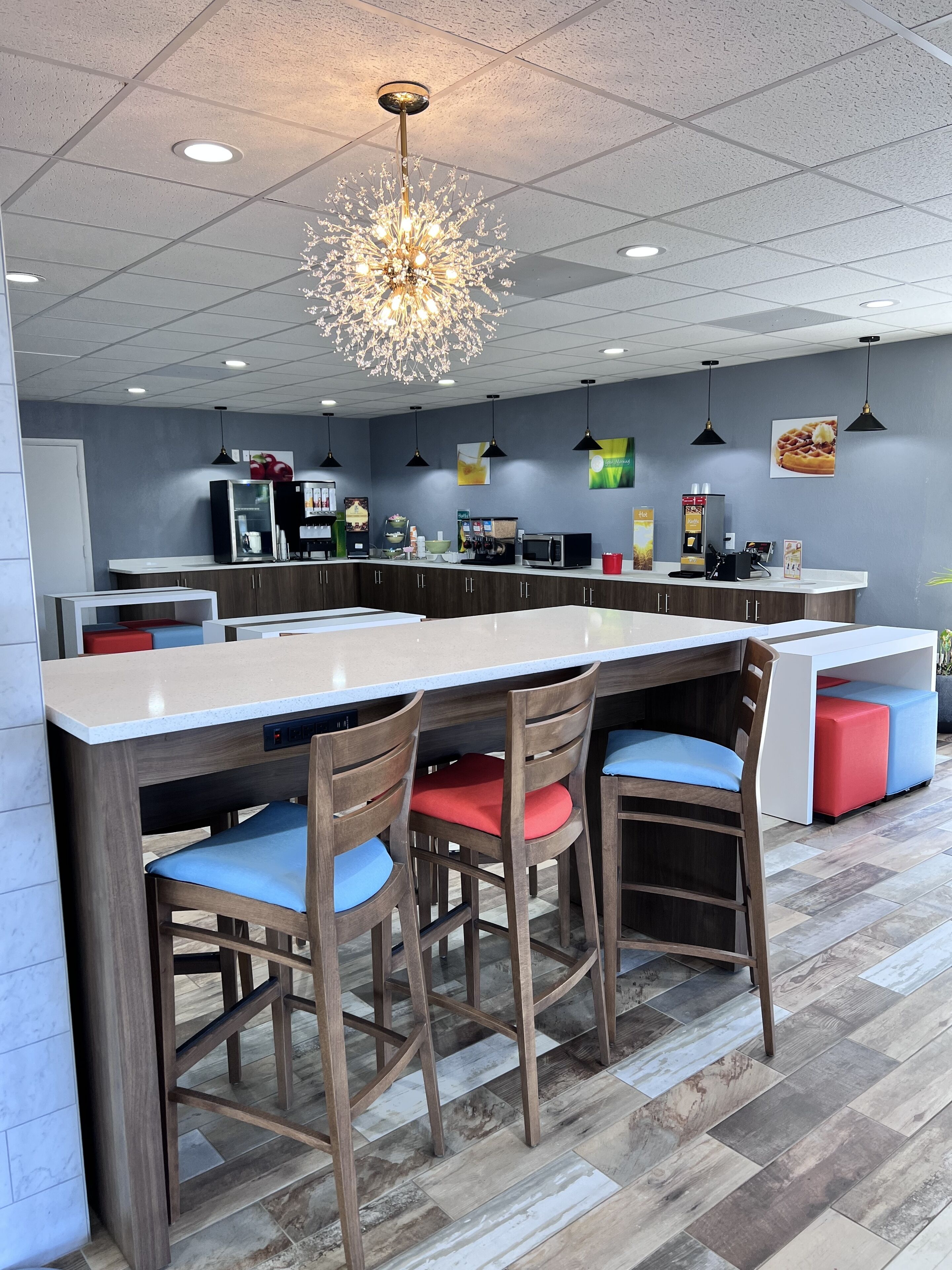 Una cocina moderna con una isla central, taburetes de bar y una araña.