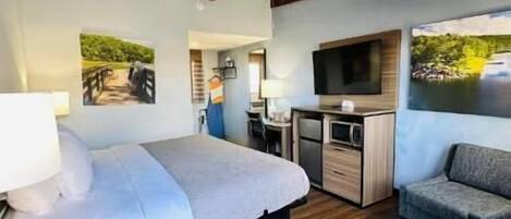 Un dormitorio con cama, escritorio, televisor y sofá.