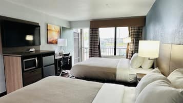 Une chambre d’hôtel avec deux lits, un bureau, une chaise, une télévision et une fenêtre avec des rideaux.
