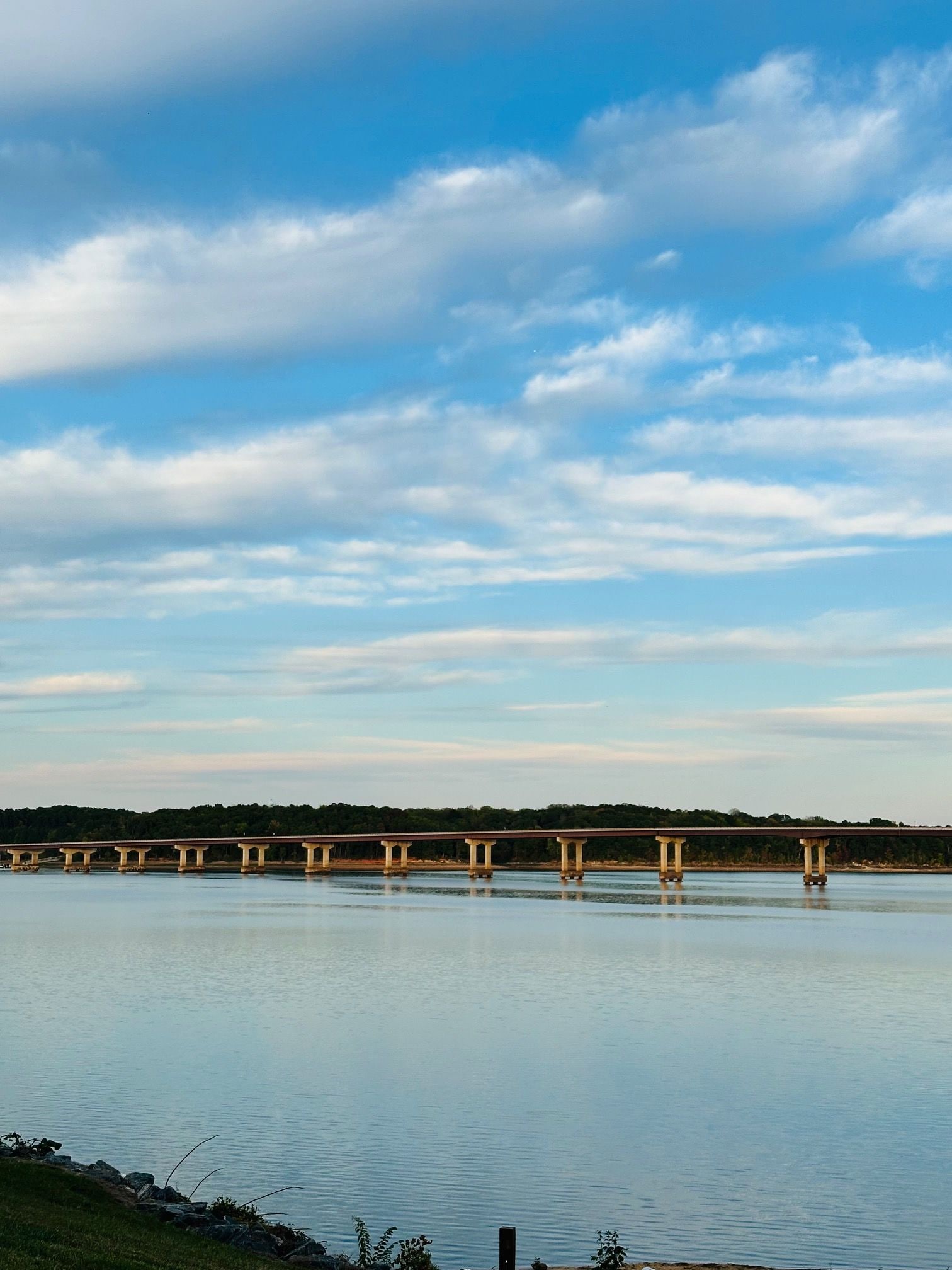 A long bridge over calm water with a clear sky.