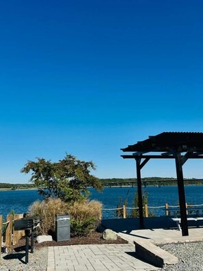 A waterfront outdoor seating area with a pergola, a table, and a grill. - Quality Inn - On The Lake Clarksville-Boydton (Clarksville)