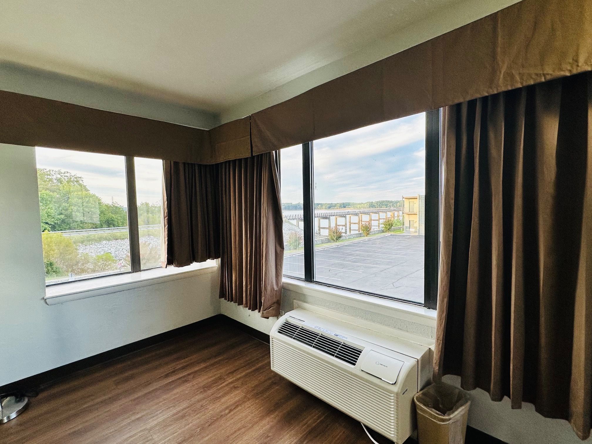 A room with large windows, a radiator, and a waste bin.