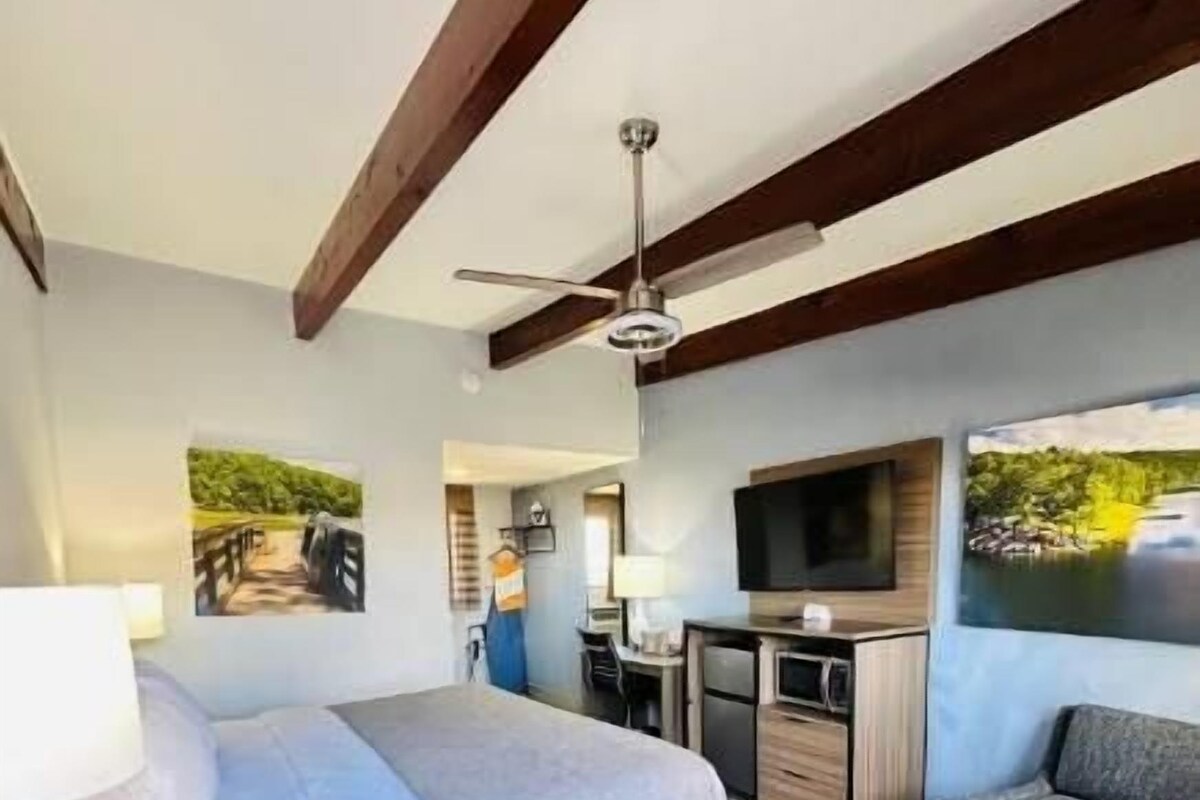 A bedroom with a bed, desk, and TV.