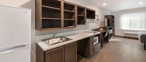 A modern kitchen with wooden cabinets, a built-in microwave, and a large window.