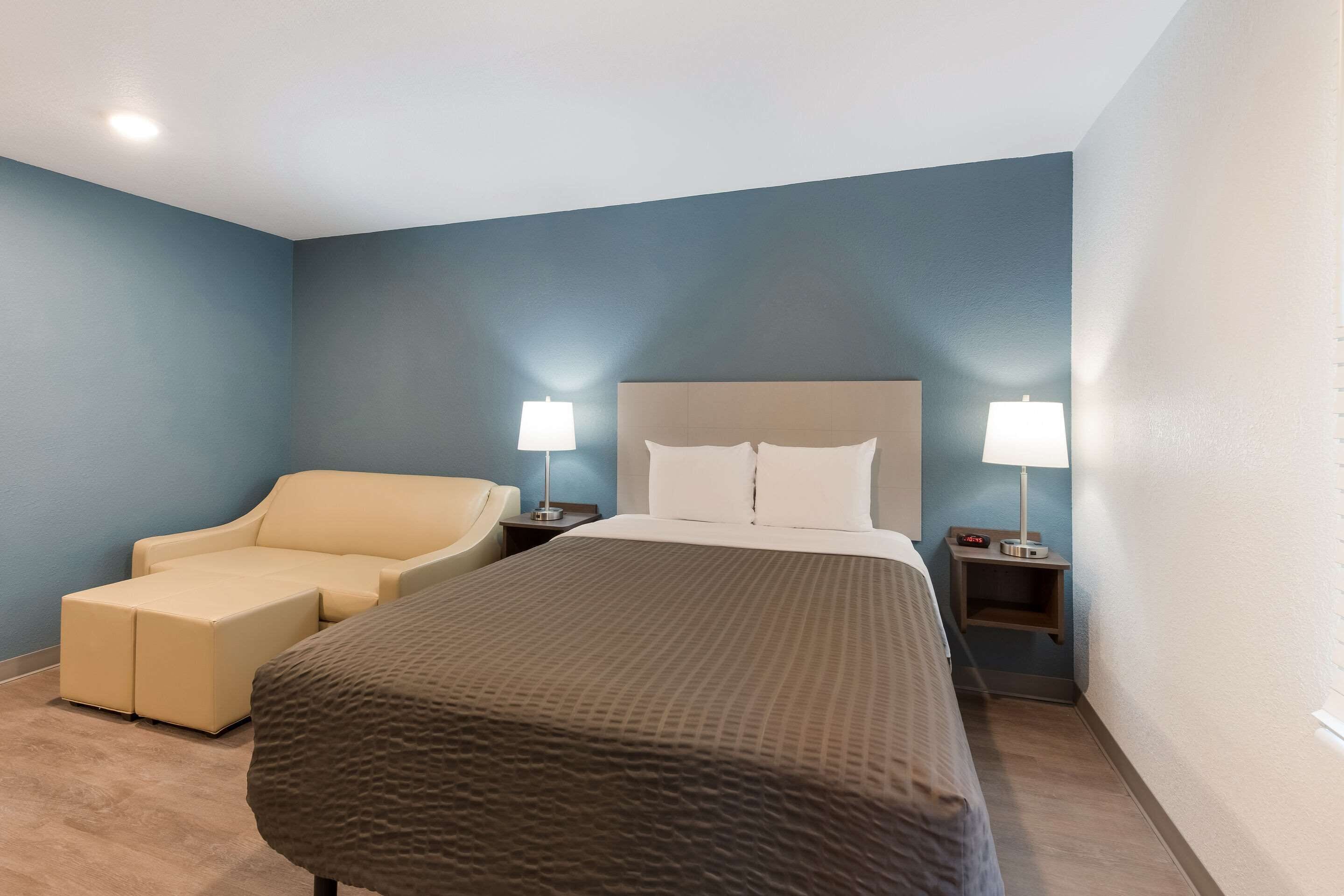 A hotel room with a bed, two bedside tables with lamps, a chair, and a small table.