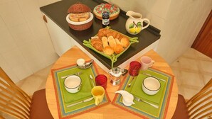 Una mesa de comedor dispuesta con platos, tazones, tazas y una cesta de pan.