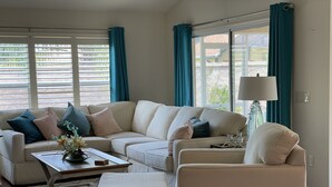 A living room with a beige sectional sofa, a matching armchair, a coffee table, and a floor lamp. - ESCAPE! to The Villages...Villa with Golf Car! (The Villages)