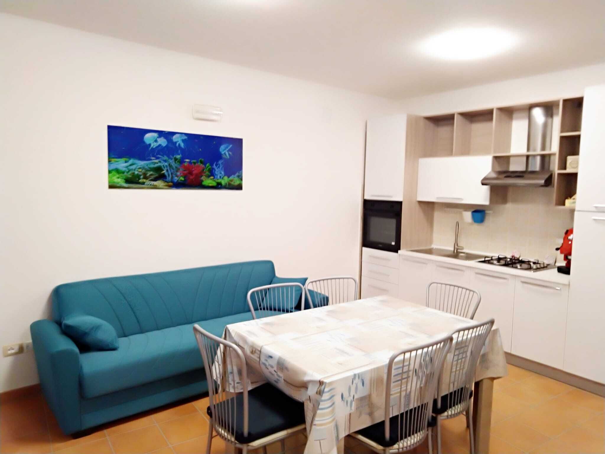 A compact living space with a kitchenette, a dining area, and a blue sofa.