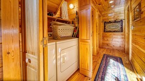 A wooden interior with a kitchen area, including a washing machine and a basket on the counter. - River Mornings, Hot tub Evenings, Repeat (Suches)