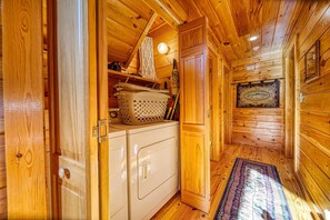 Un intérieur en bois comprenant un coin cuisine, avec un lave-linge et un panier posé sur le plan de travail.